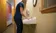 A picture of a women in a blue shirt washing her hands