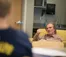 A picture of Mark Tazlaar sitting in a chair, looking at a student