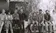 A black and white photo of a group of students sitting on car hoods