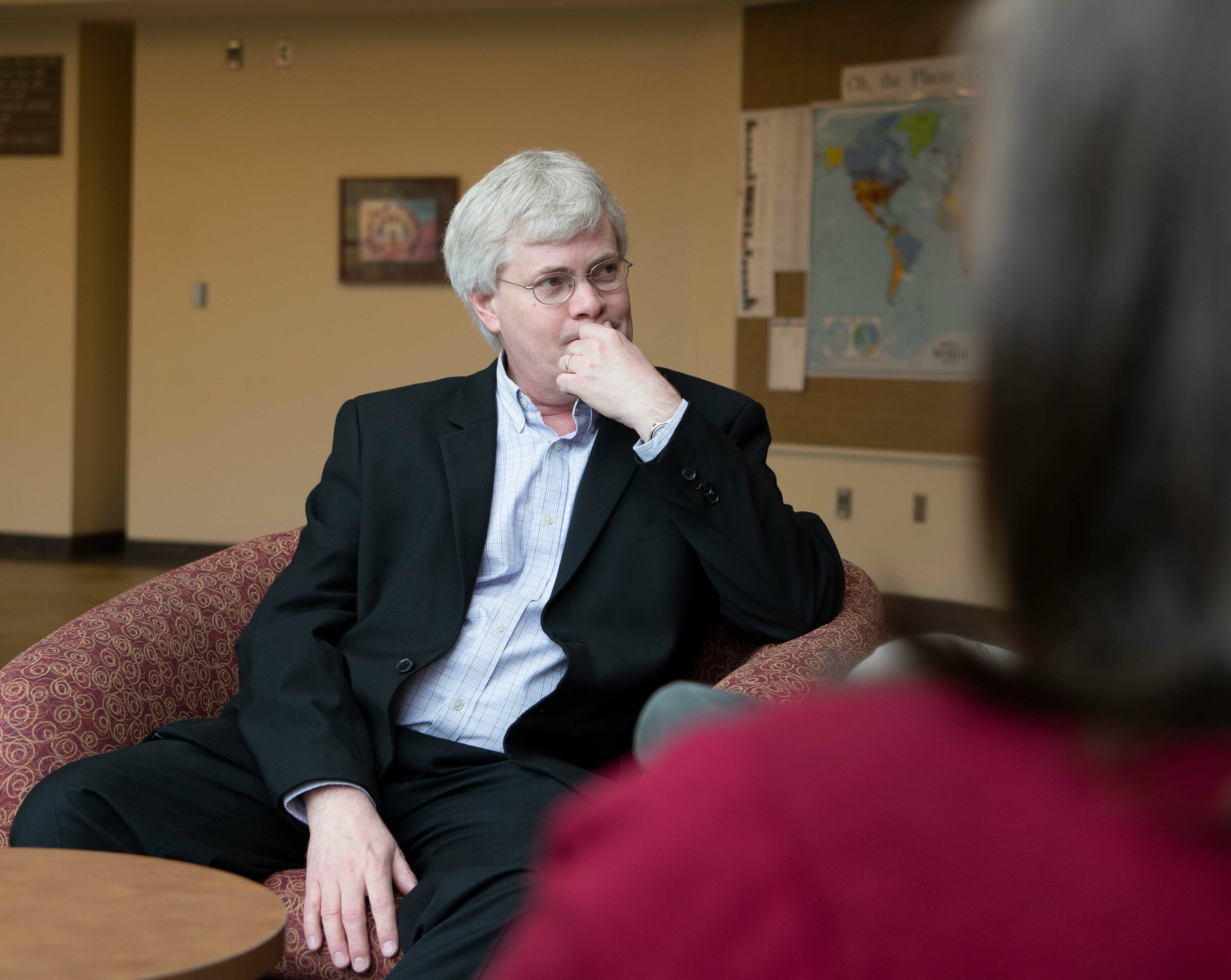 Political science professor sits in thoughtful discussion with others