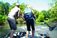 A picture of two people on a boat with a net while fish jump out of the river