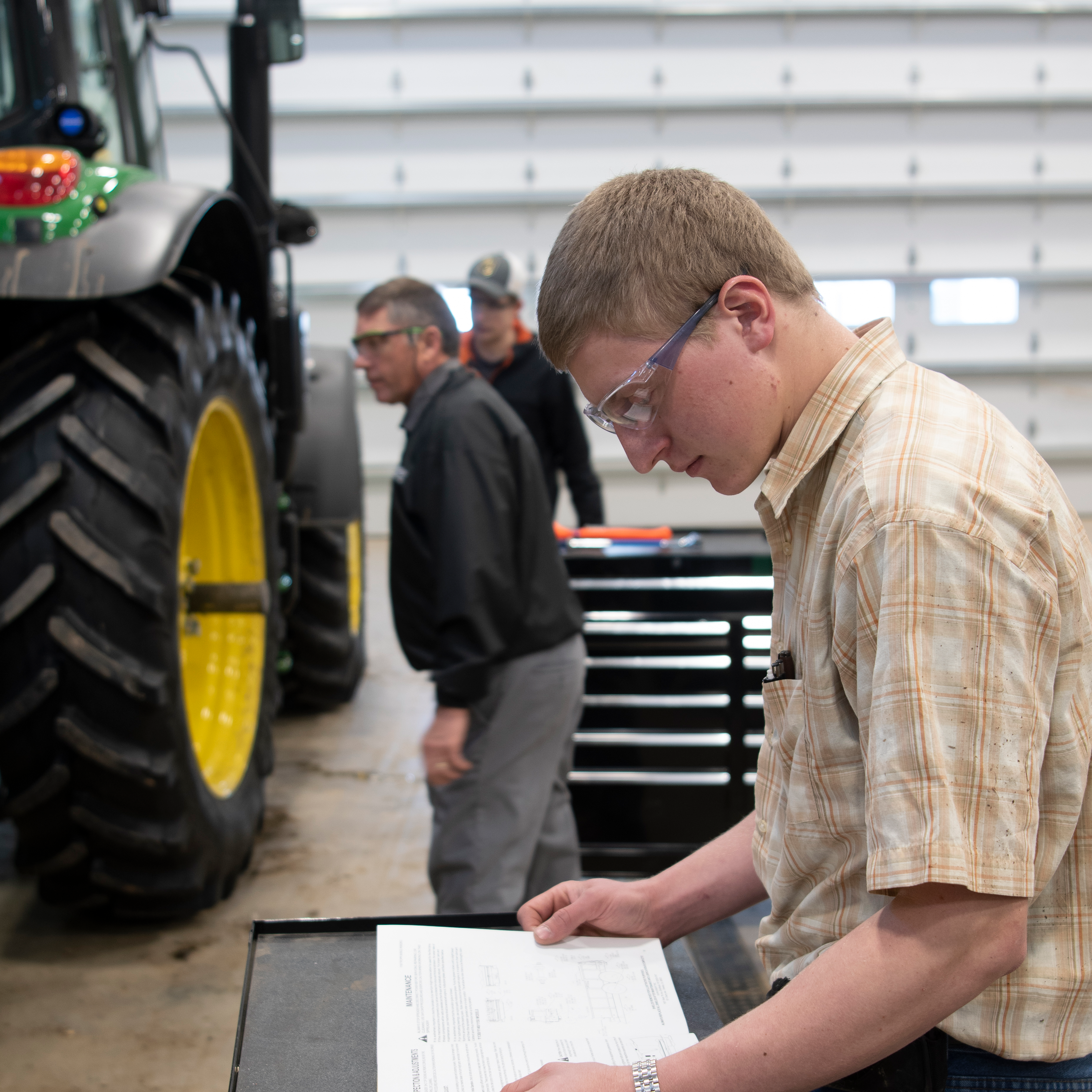 A male student reviews a maintenance manual in the high bay of the Agriculture Stewardship Center