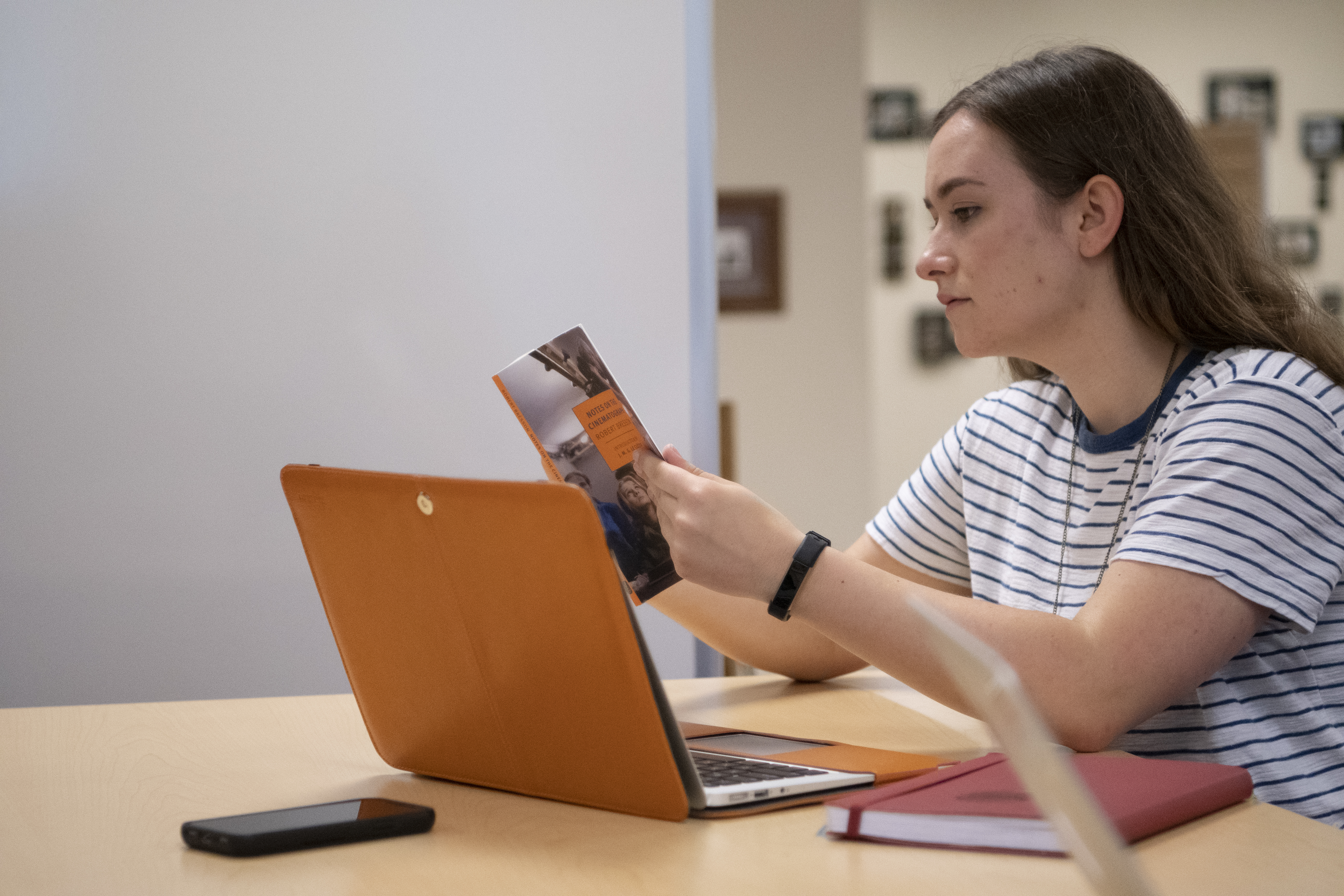 Female student uses computer and book to complete an assignment