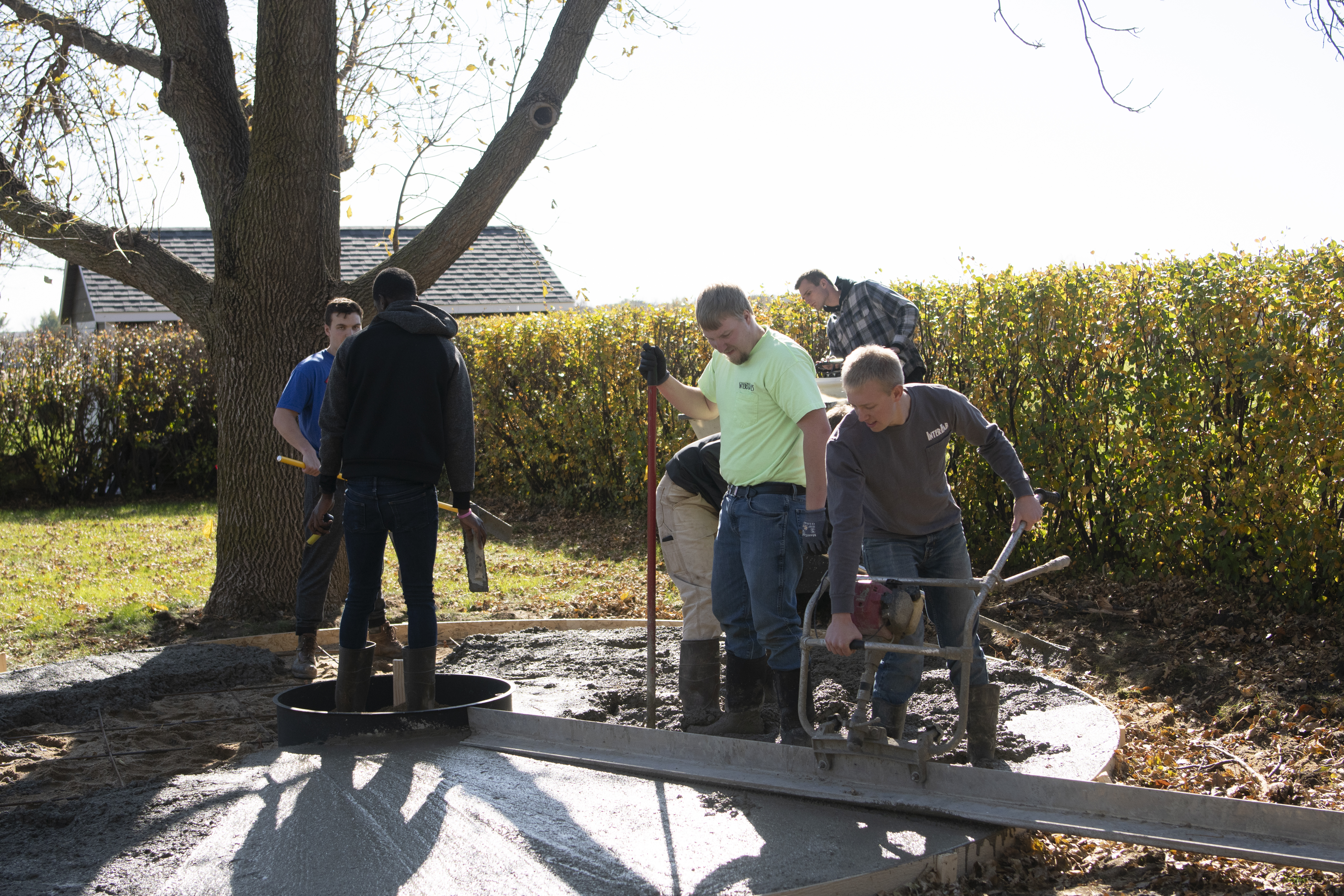 Students work pouring concrete for a fire pit