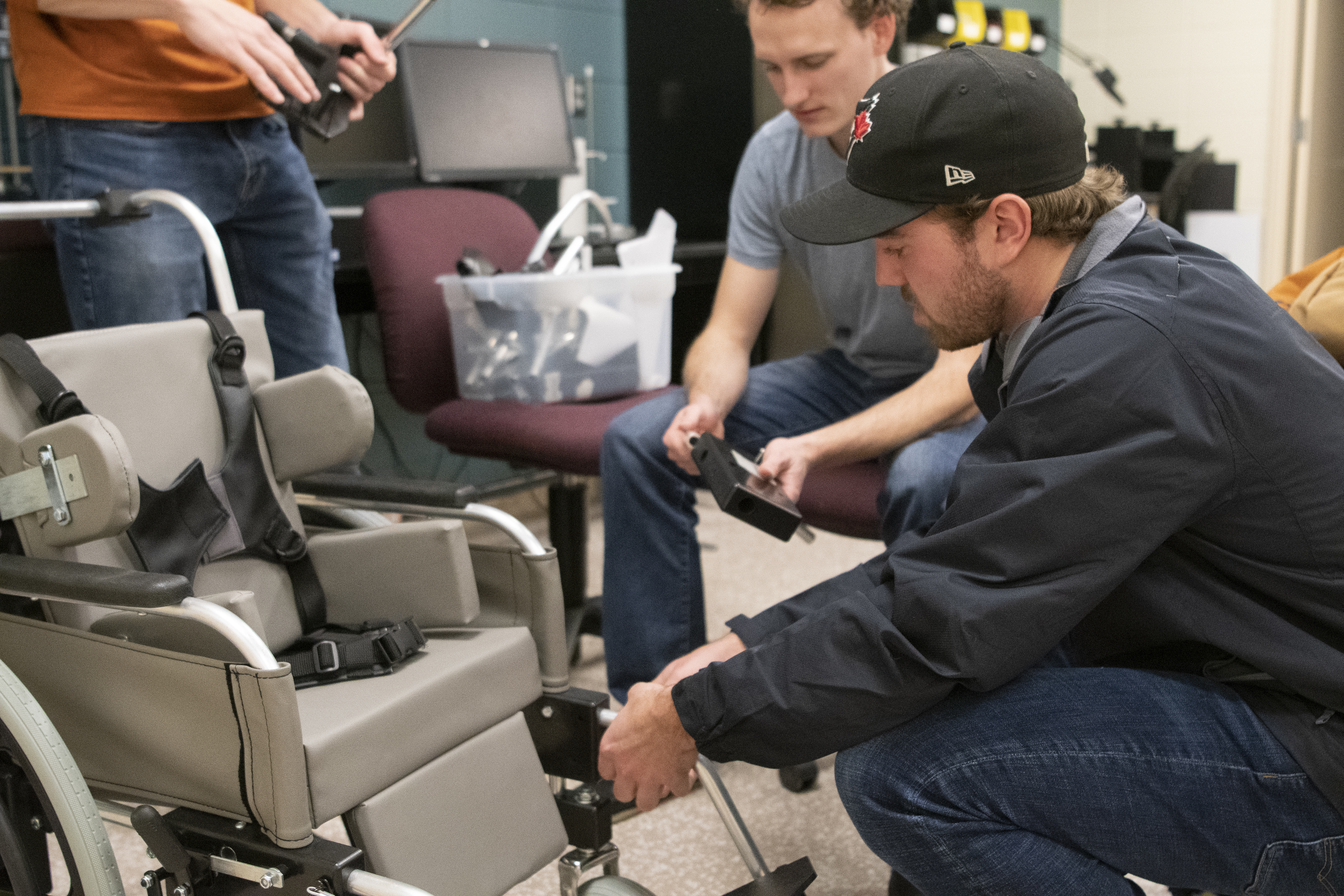 A male students works alongside others on a wheelchair project