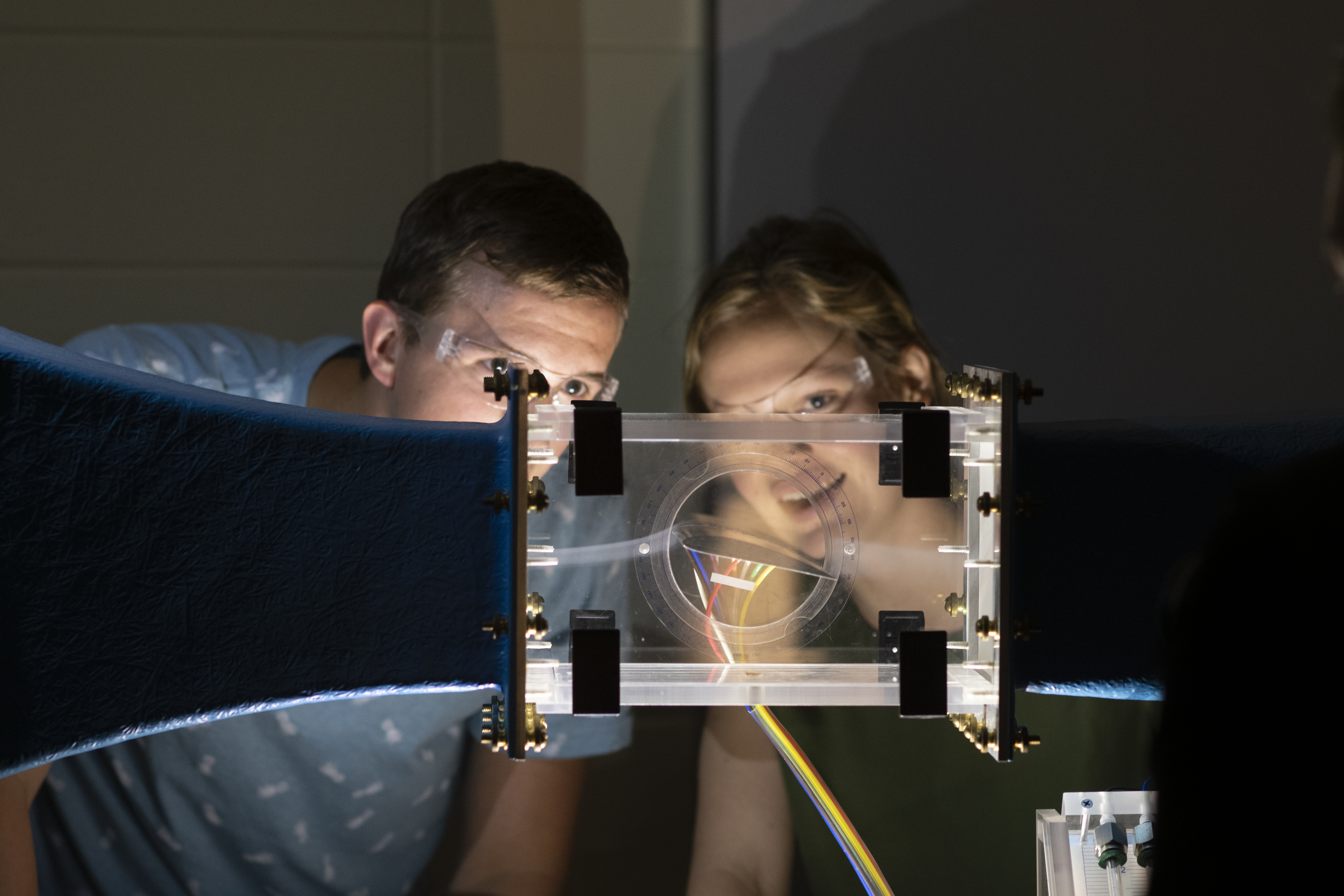 Two students watch a wind tunnel in the lab