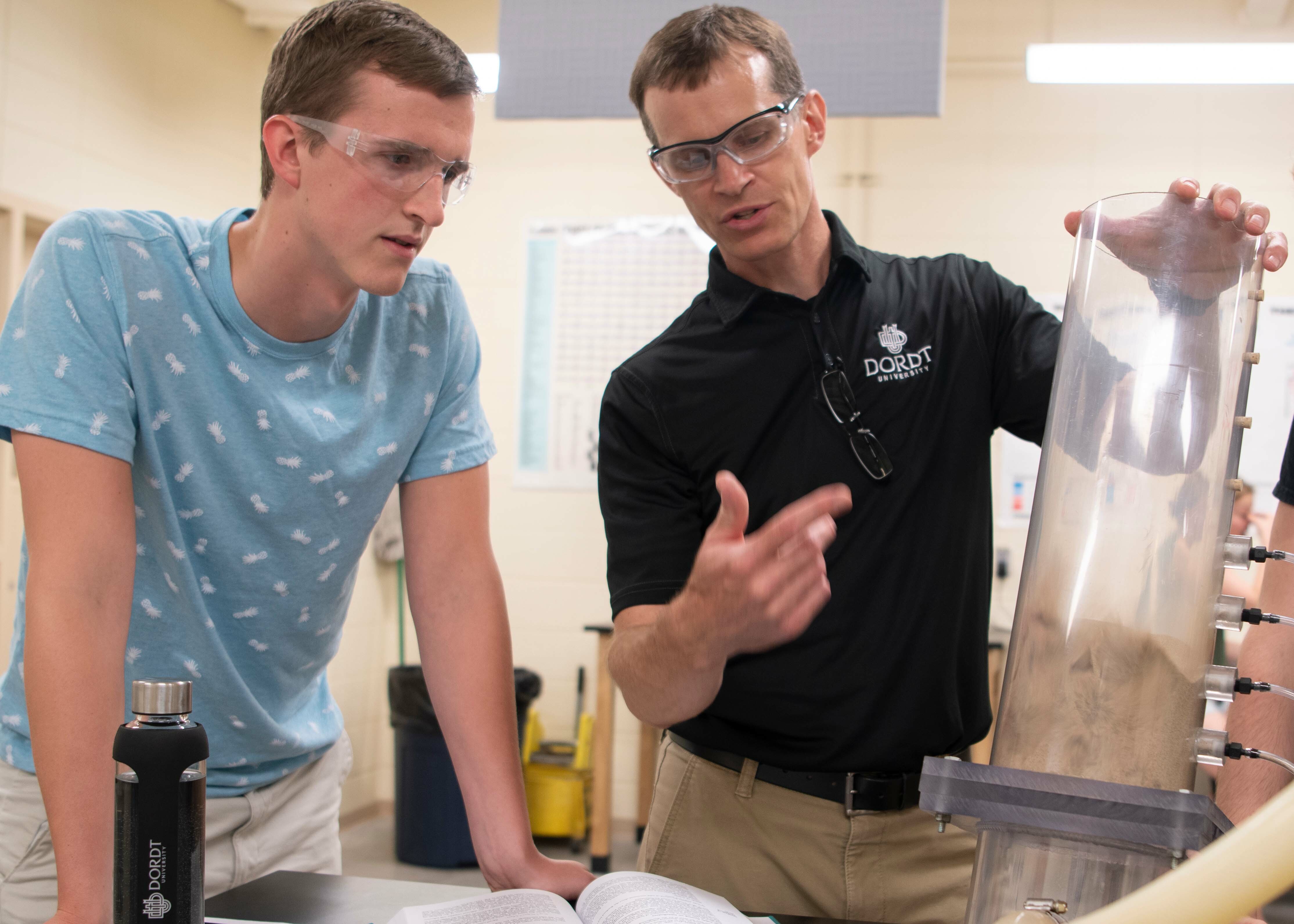 A male student and professor discuss a demonstration in the lab
