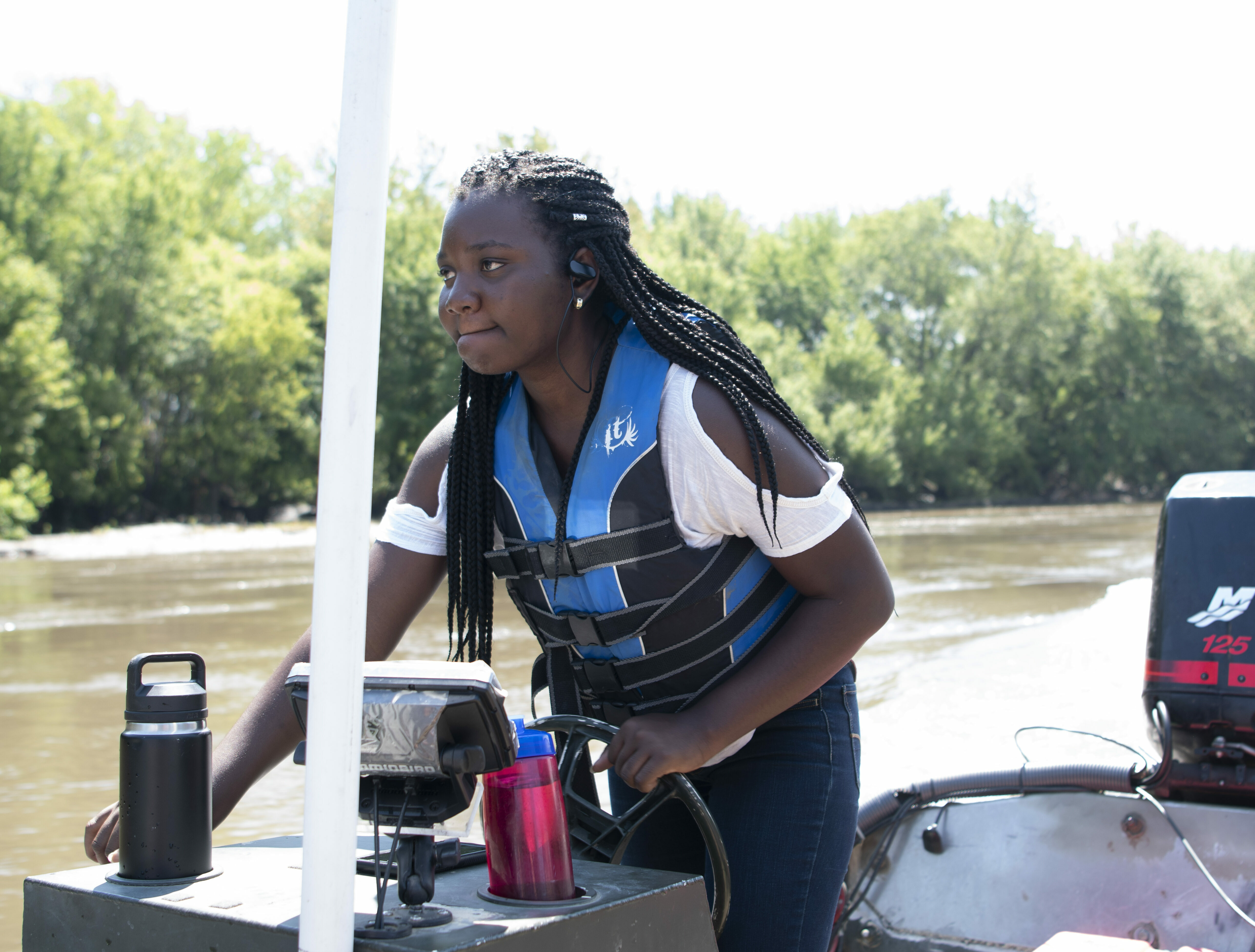 Female student drives boat on river for carp study project