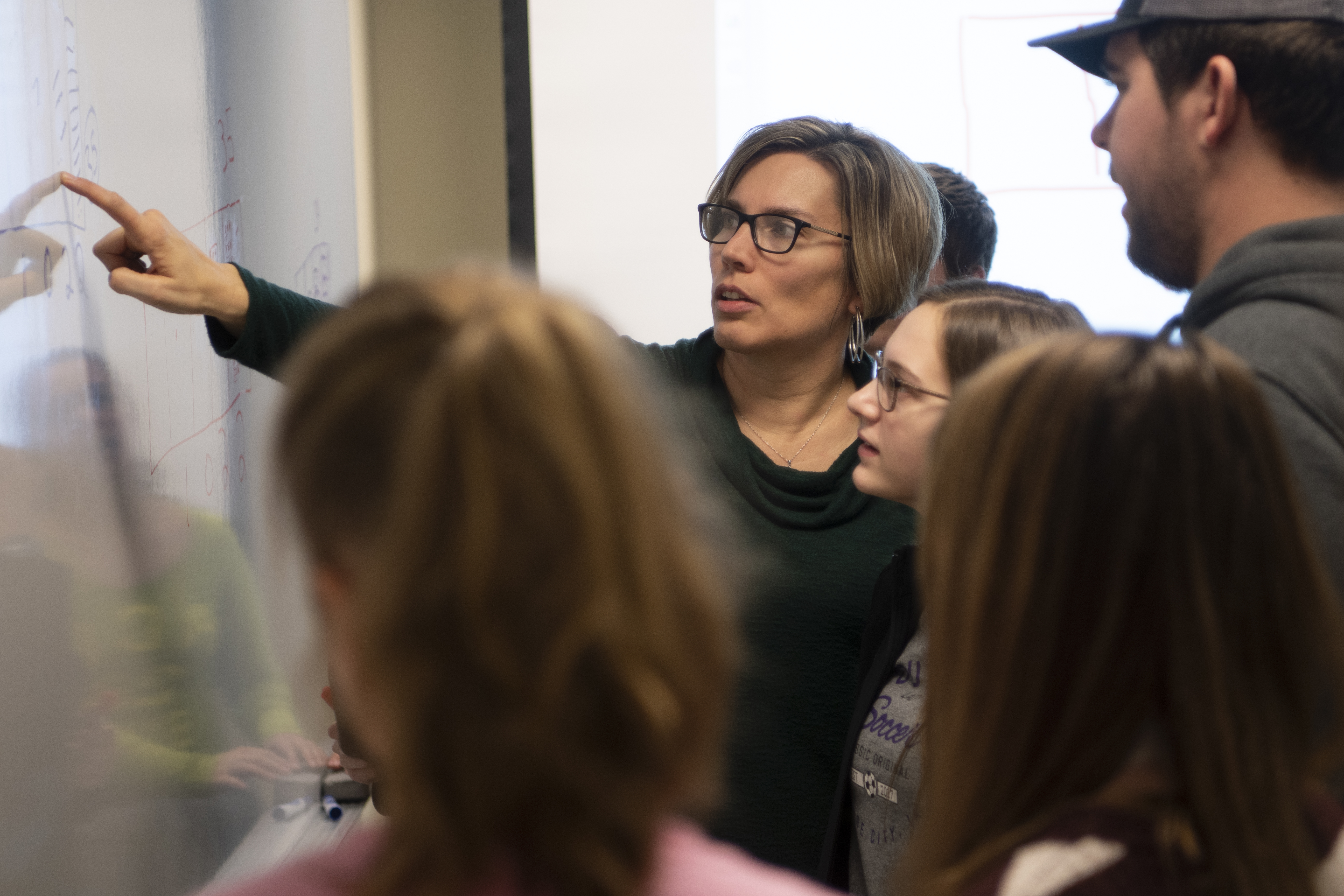 Dr. Zonnefeld points to the whiteboard in discussion with students