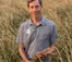 Man standing in field of grain holds onto bunch of it
