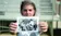 A picture of a student holding a black and white photo for the camera