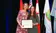 A picture of two women holding an award while standing in front of flags