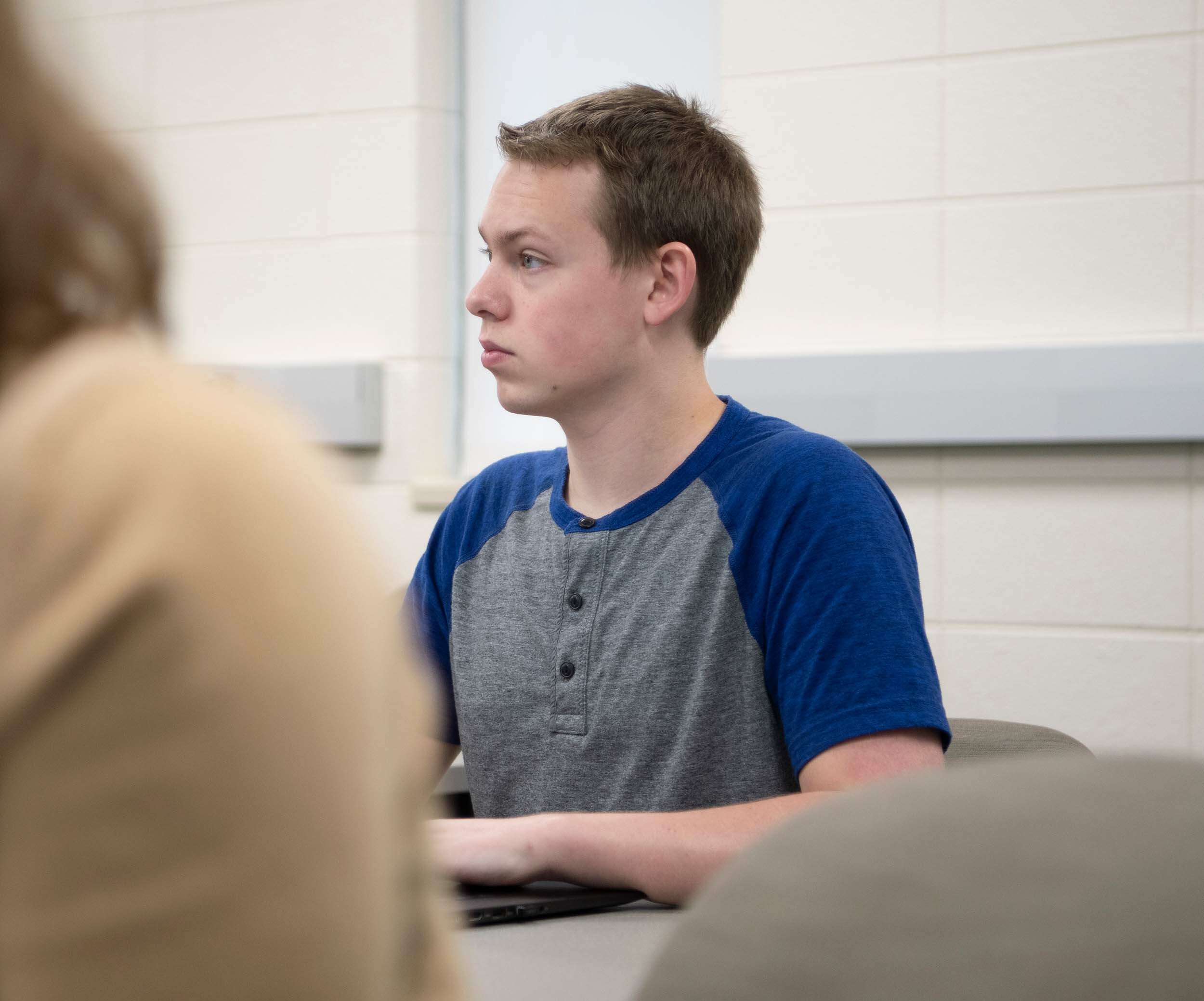 A male student sits and listens in class