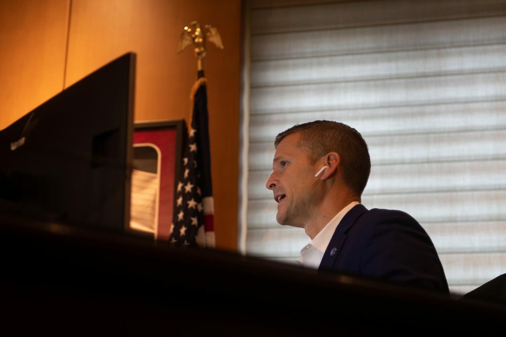 A government official sitting at his desk talks on the phone using a wireless headset