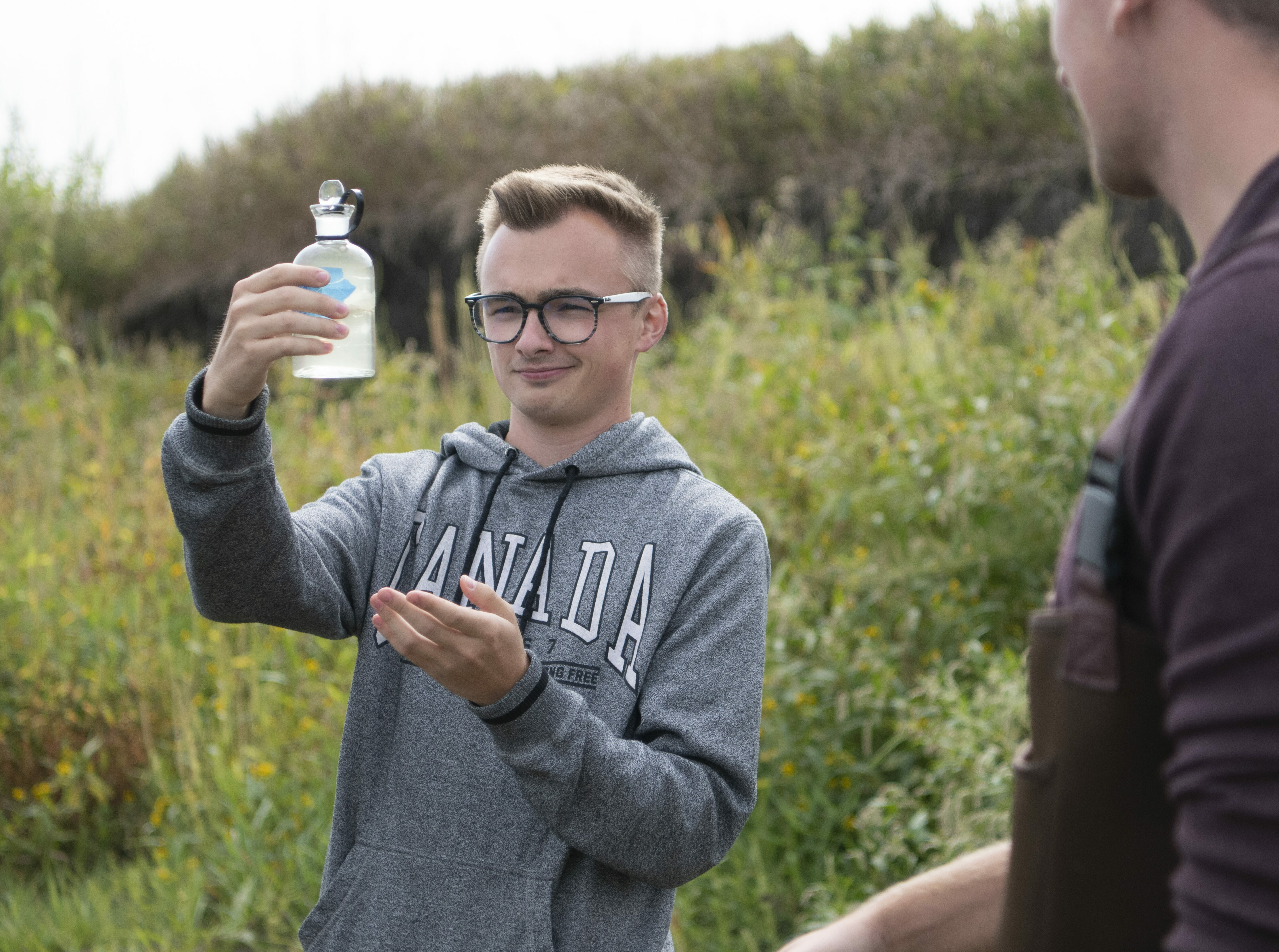 Male student looks at water sample from river
