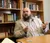 A man sits in front of a bookshelf in his office, and speaks to someone while gesturing with his hands