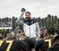 A coach takes off his hat to pray with the football team