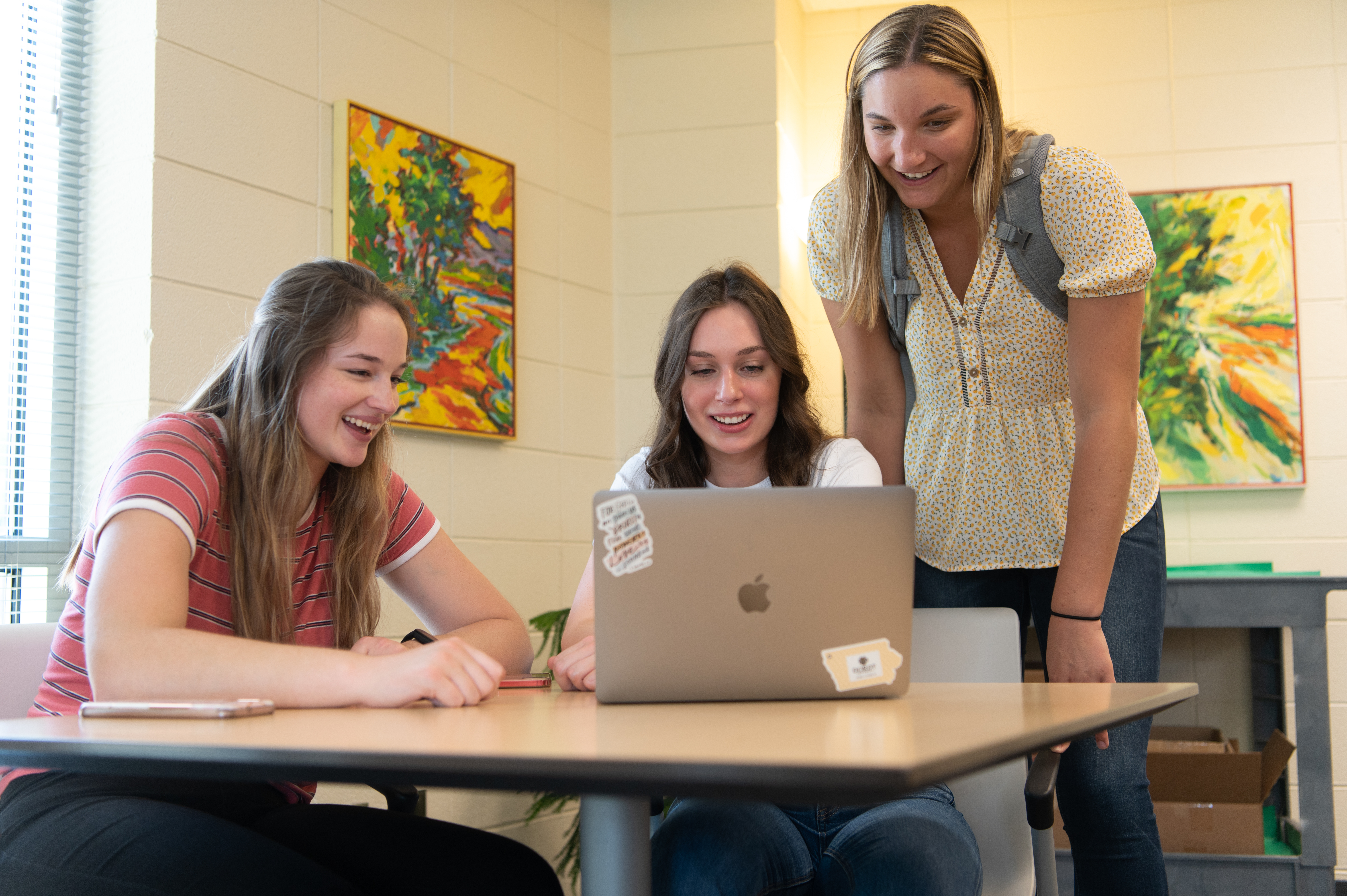 Three female students work on a laptop