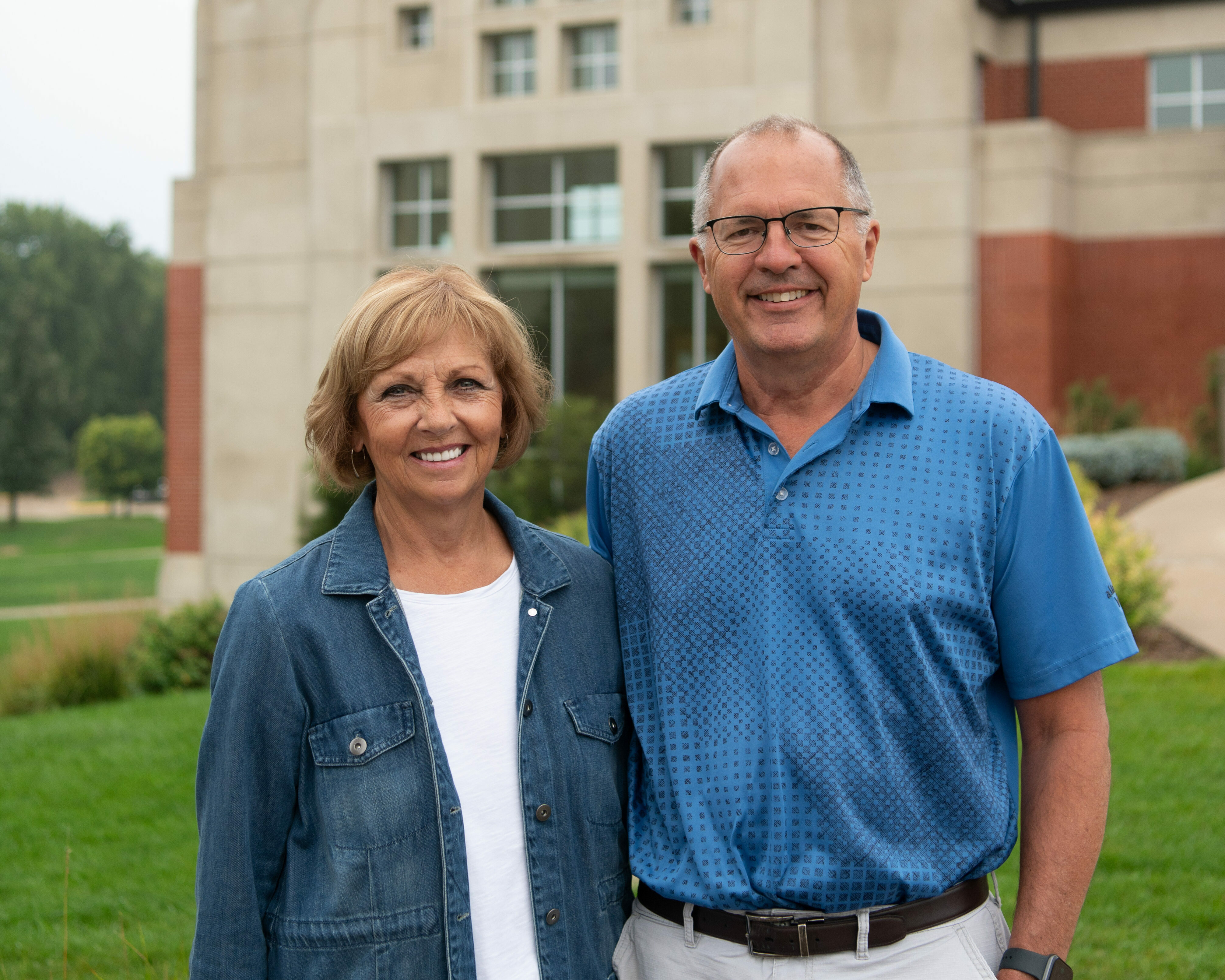 A couple poses for a picture in front of the campus center
