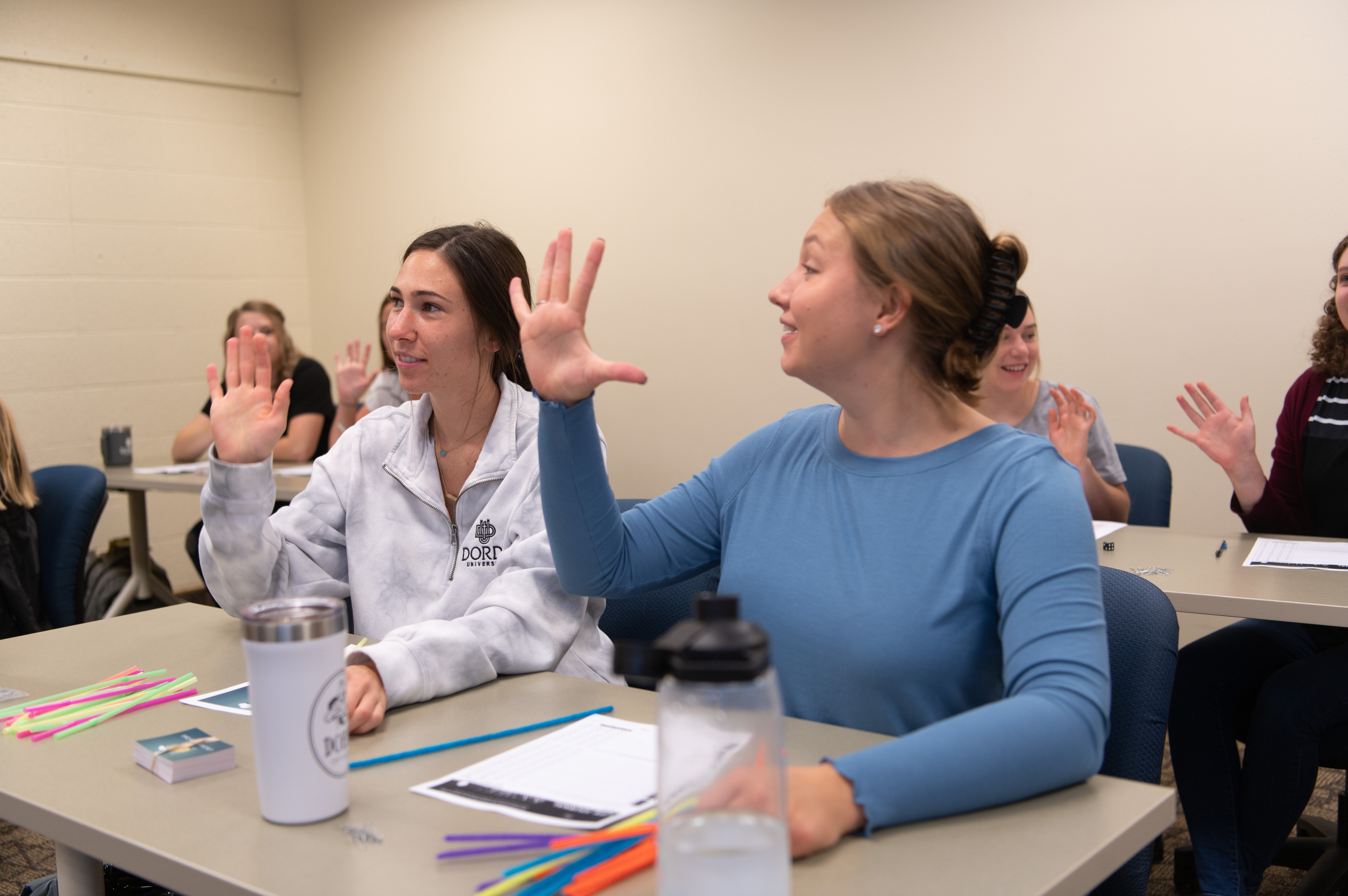 Students raise their hands to answer a question in class