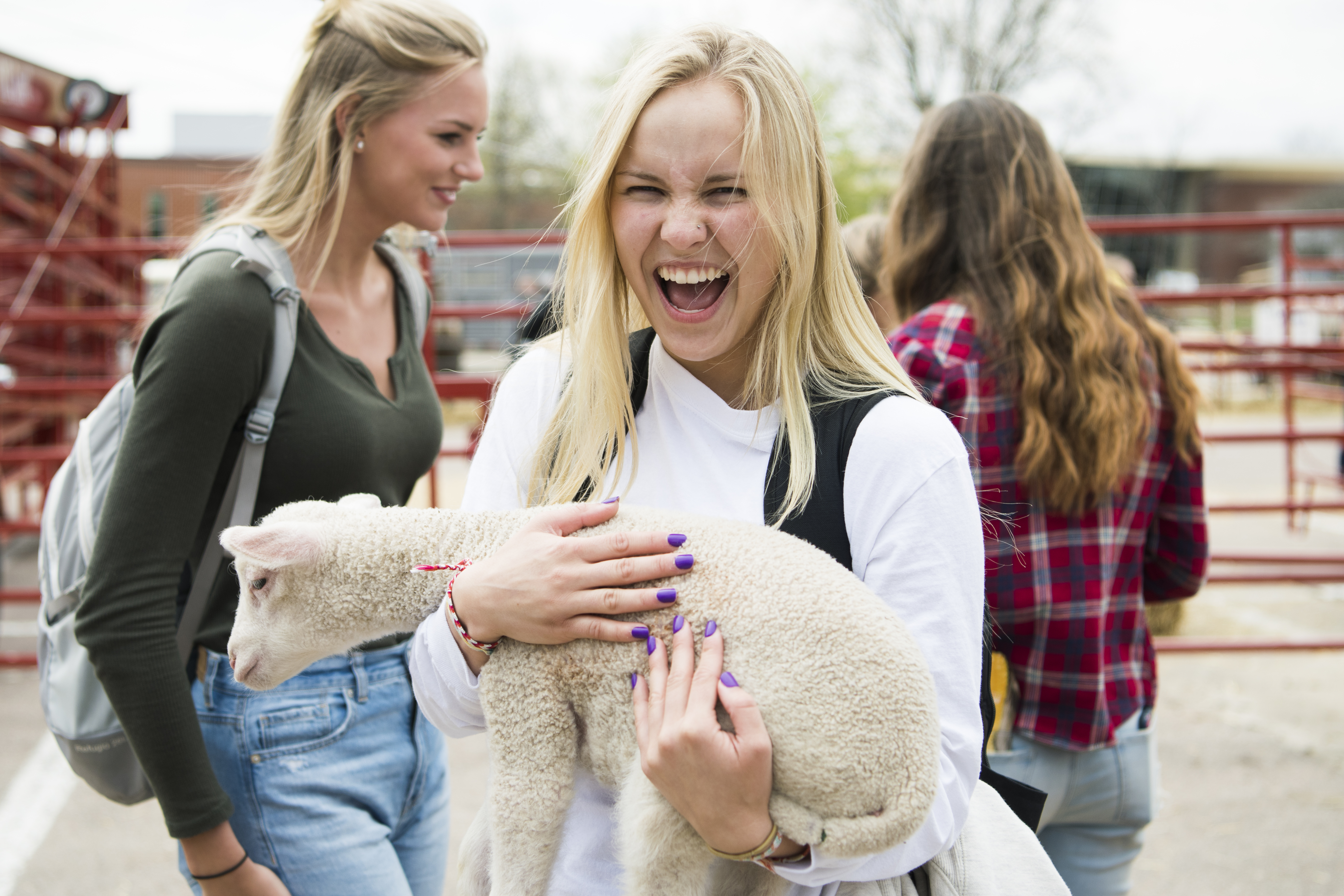 A female student smiles while holding a lamb