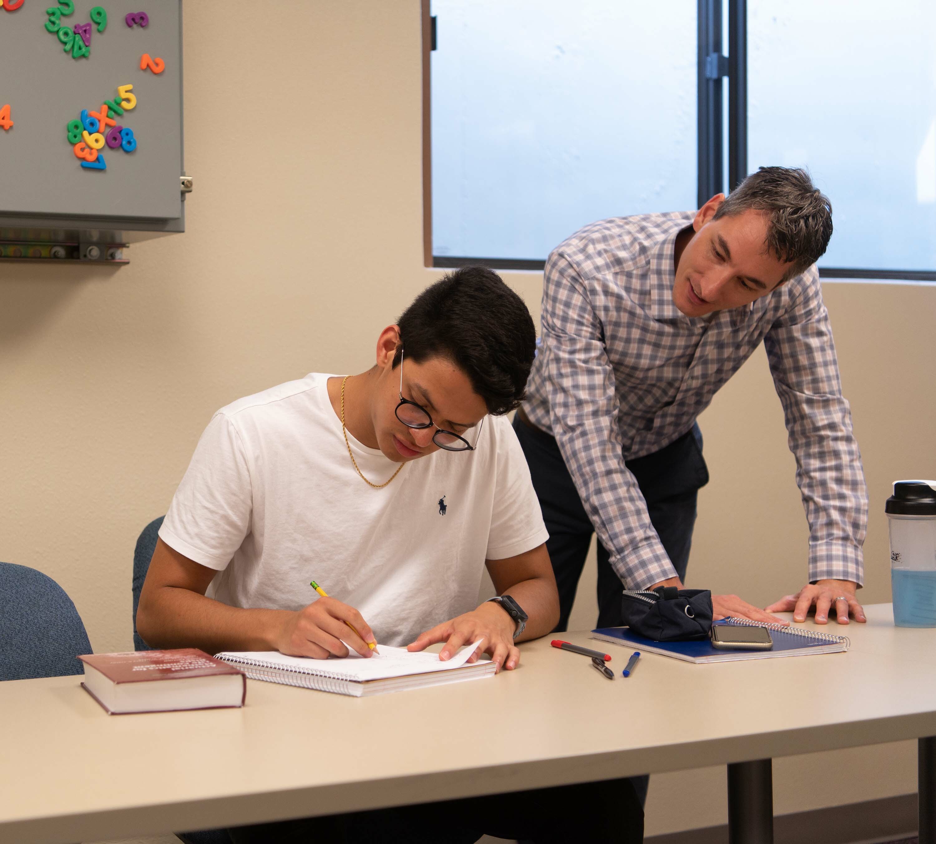 Actuarial science professor leans over to check in with a student and their work