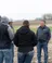 A group of students talk with Professor Vos in a field