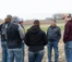 A group of students talk with Professor Vos in a field