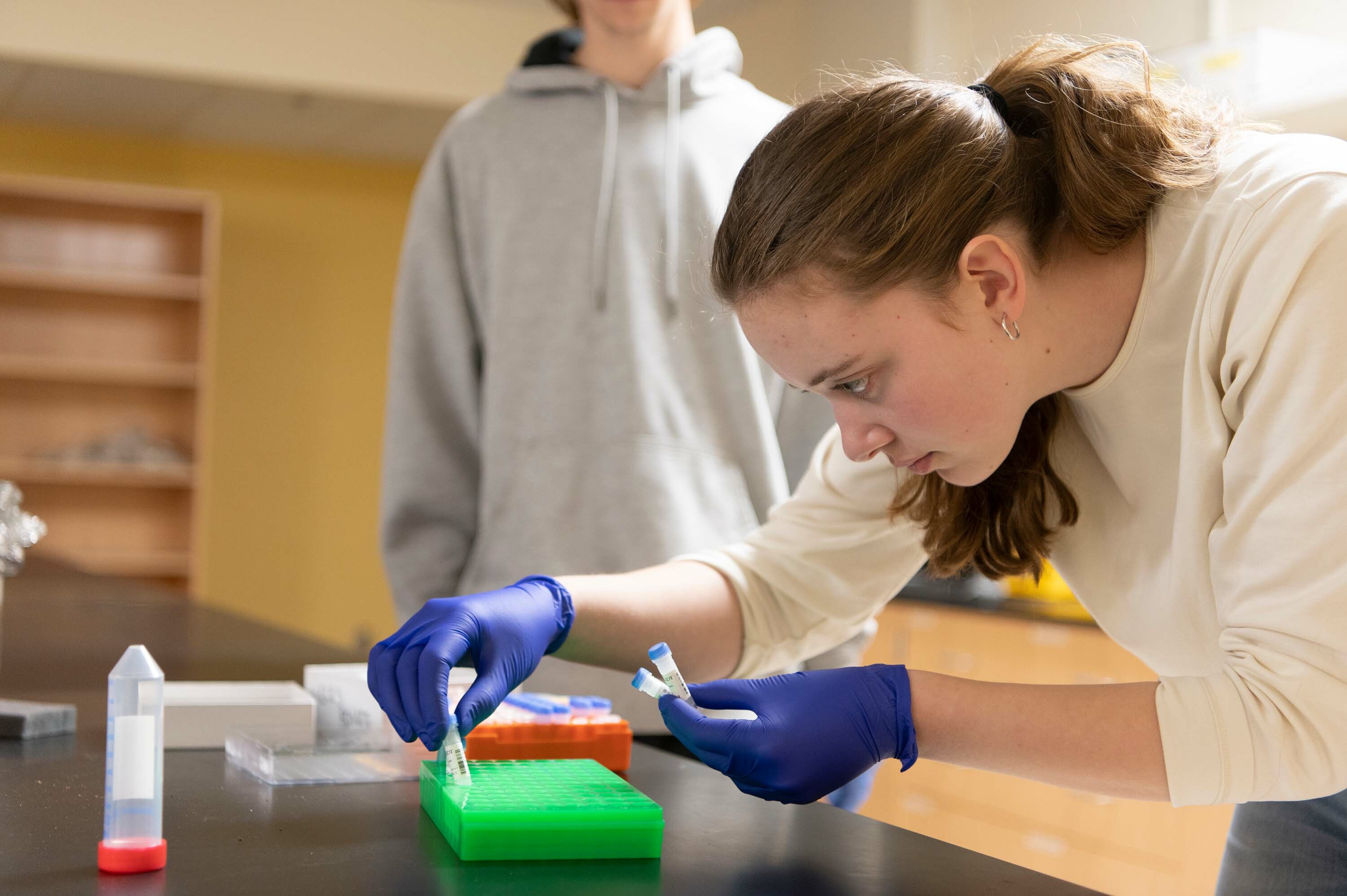 a female student sorts small plastic sample containers