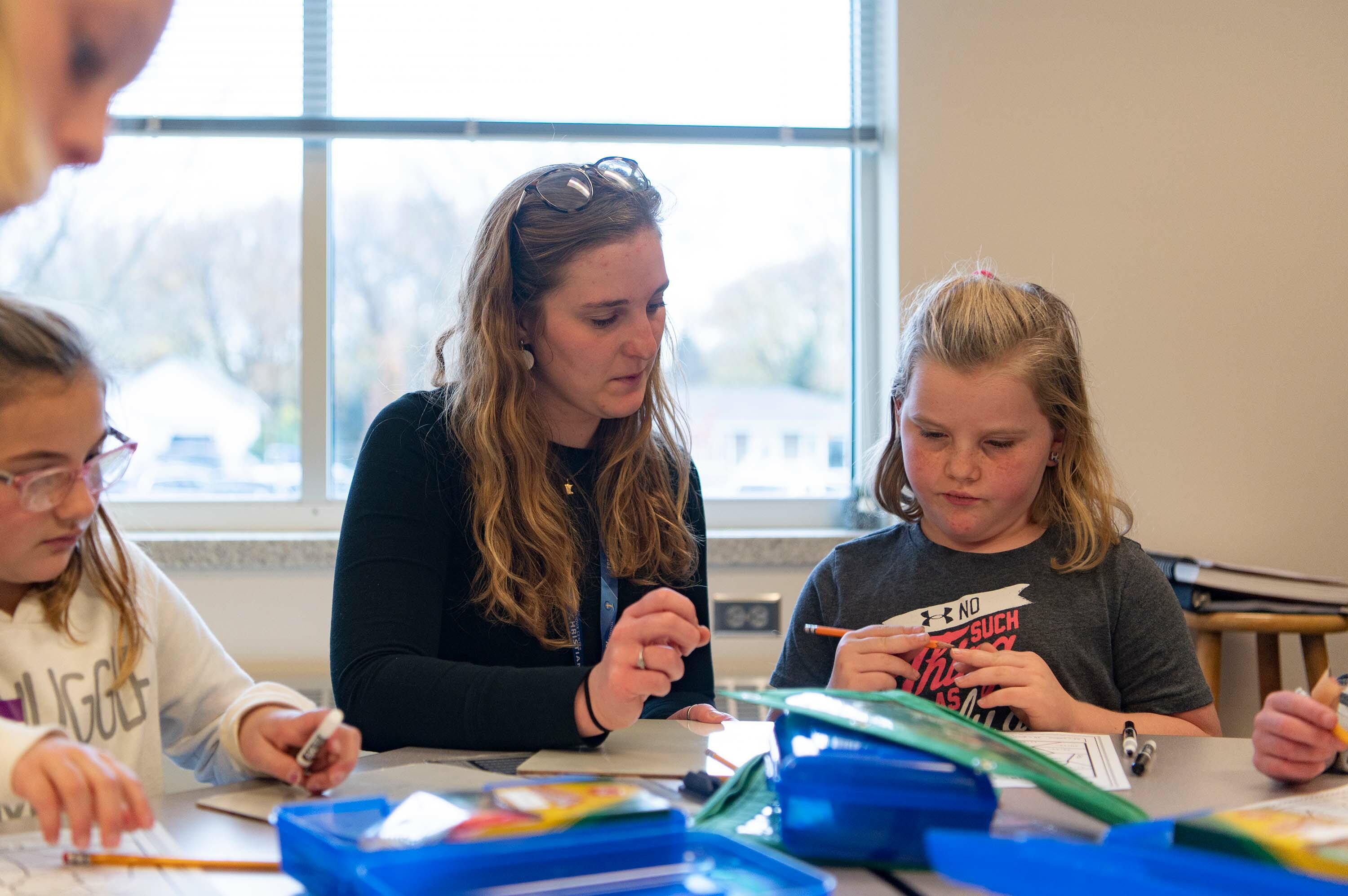 A female Dordt student works with a younger student at an elementary school