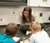 A Dordt student leans over two young students in class as they work on math