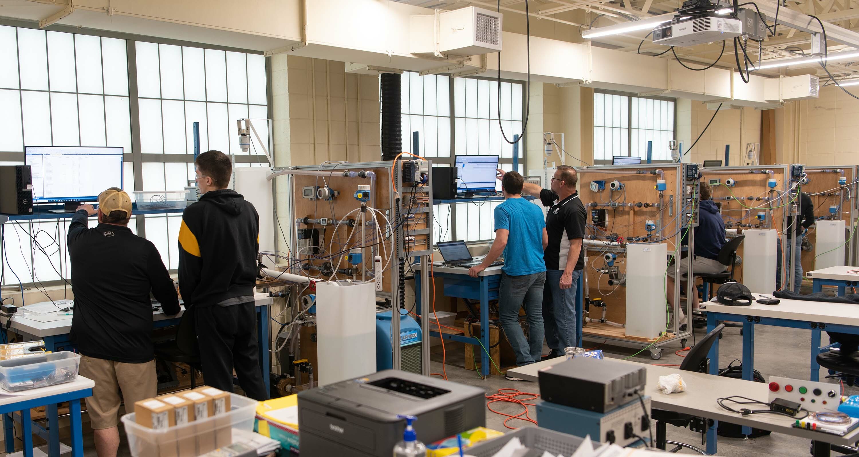 Students stand at their stations in the engineering lab