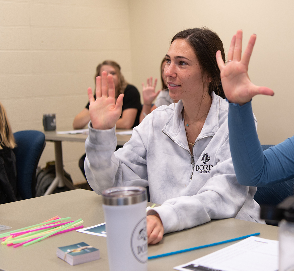 Students in class raise hands at desks