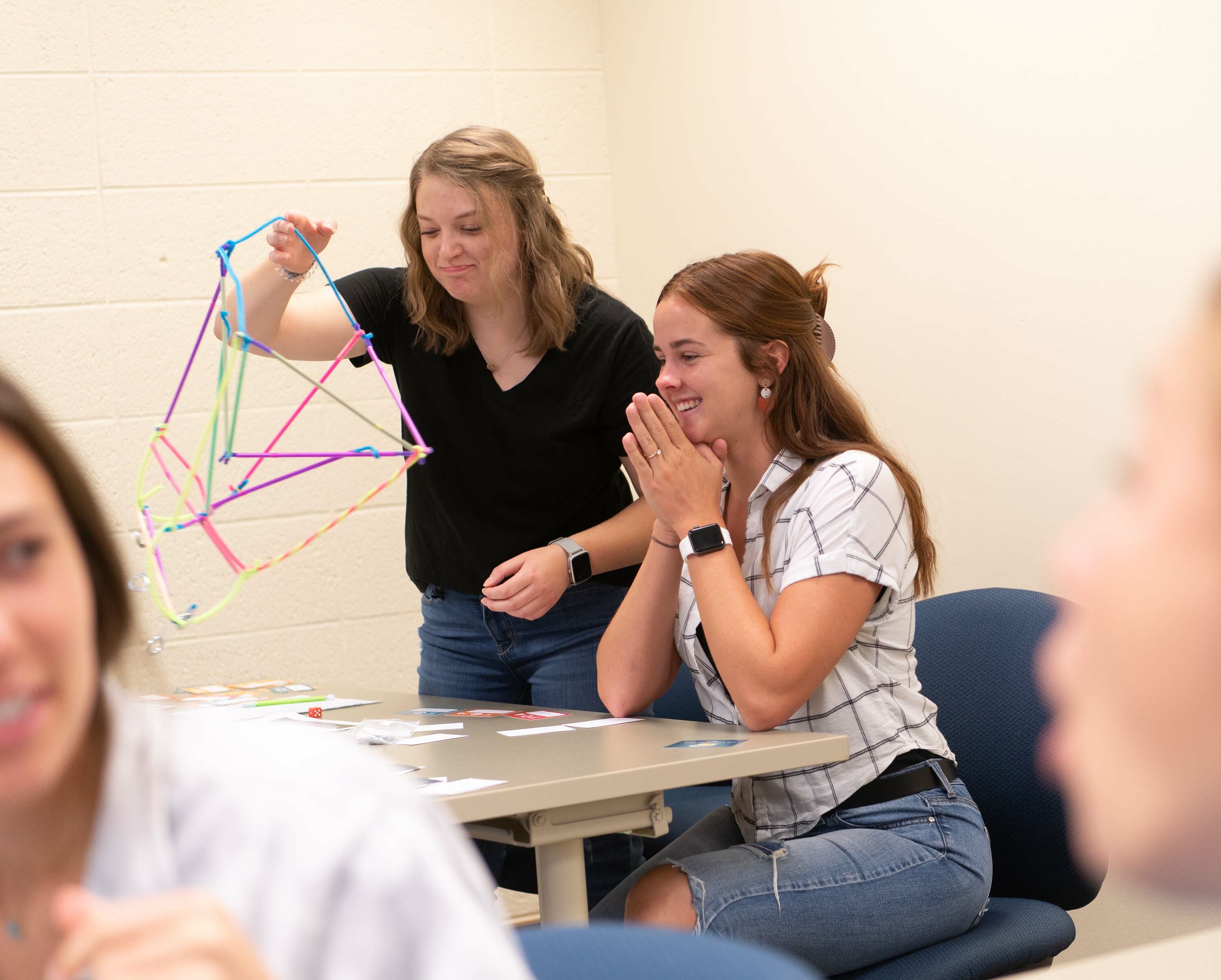 Two girls look at a creation of pipe cleaners as they do the brain game in class