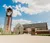 Clocktower and building under bright blue sky with puffy clouds