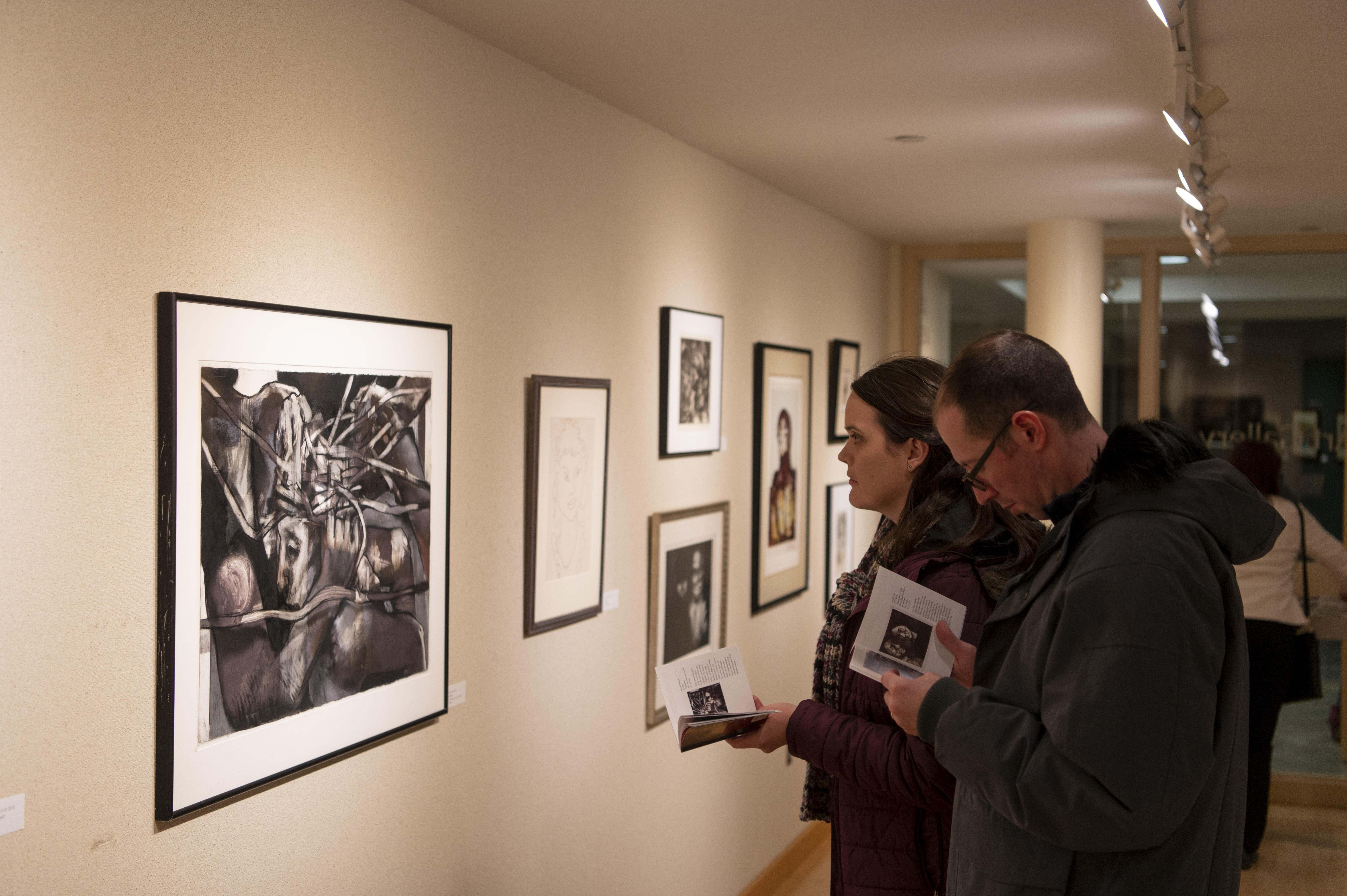 People look at drawings in an art gallary