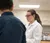 A student in a lab coat interacts with a professor in a lab