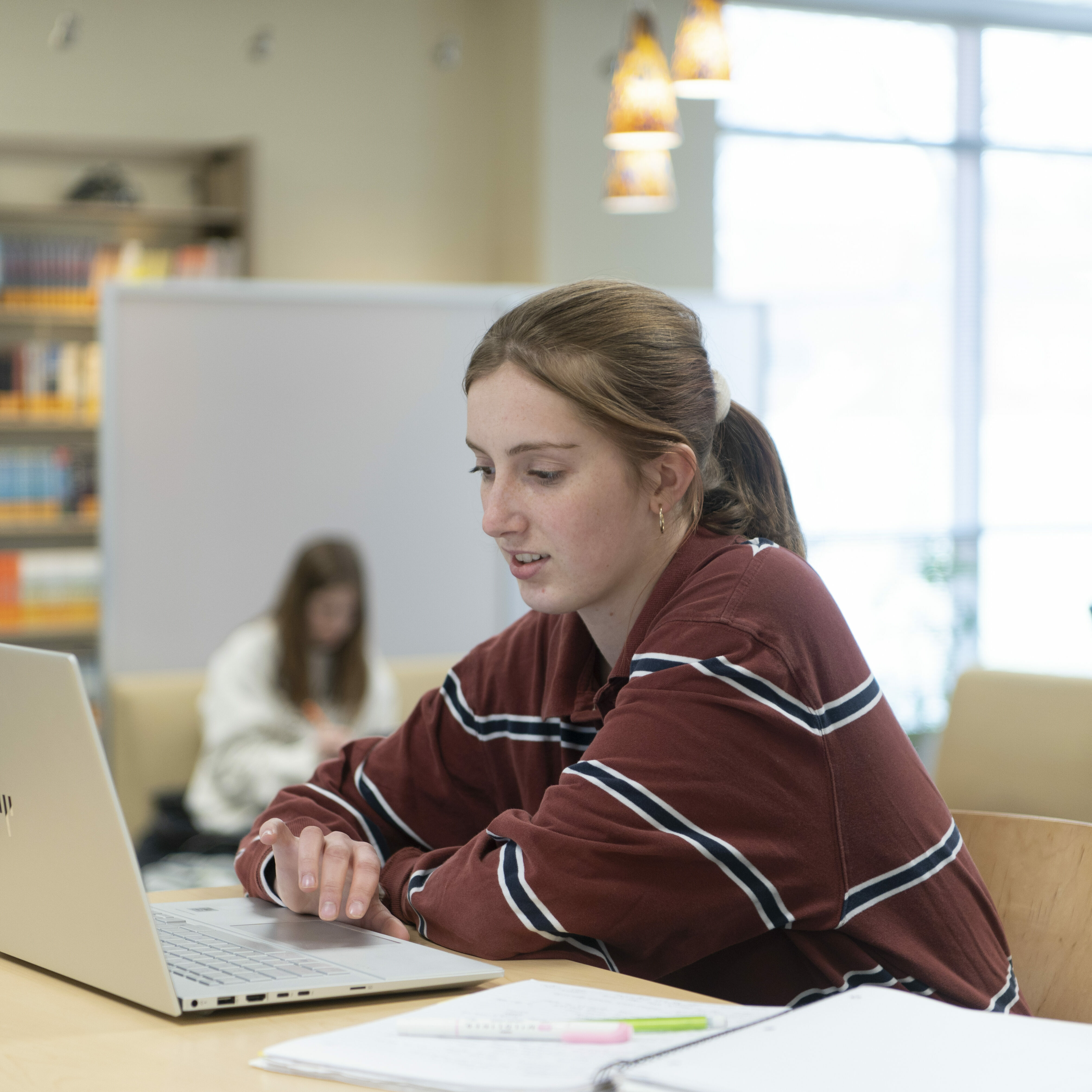 A female student works on a laptop in the library