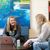 Two students chat over laptops in the library