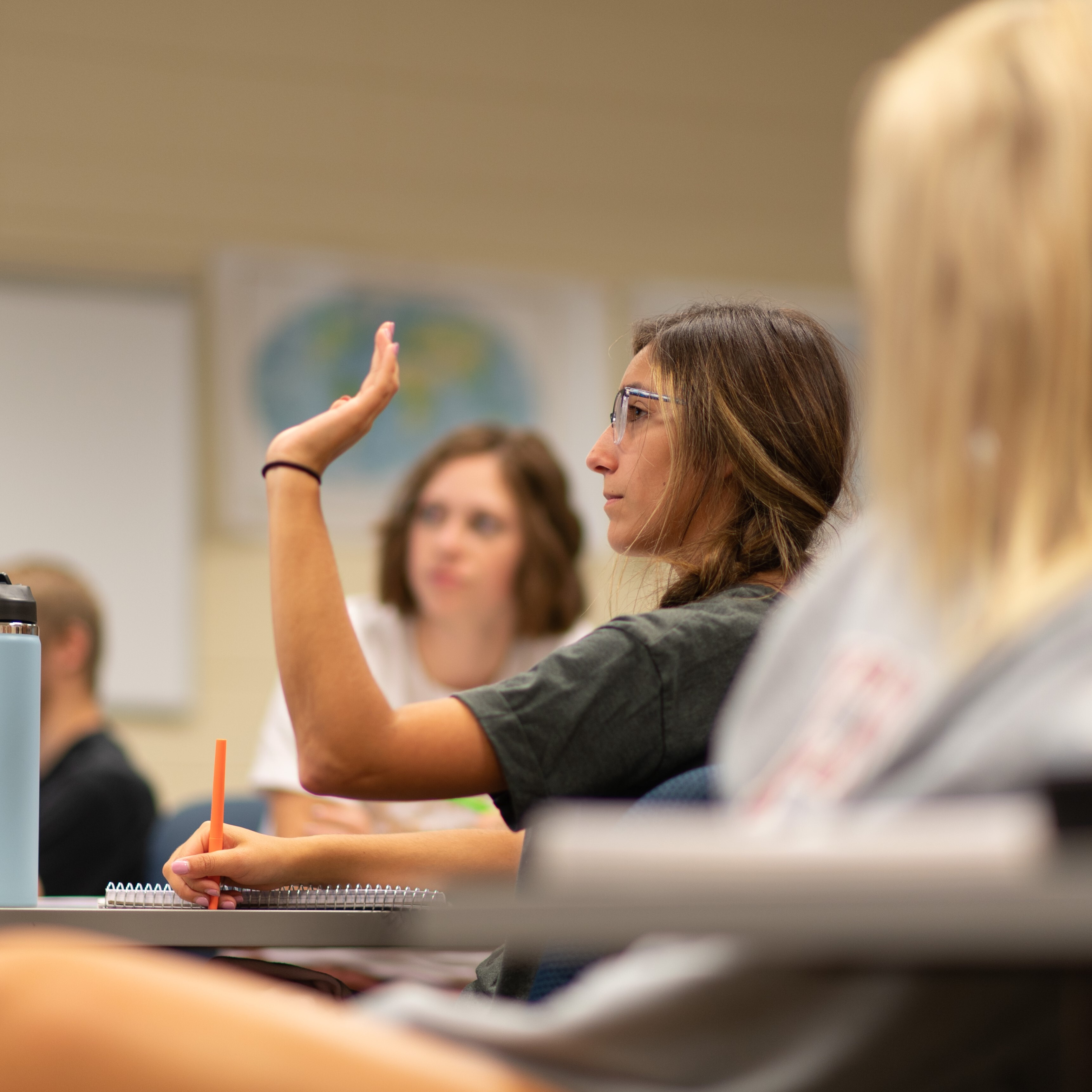 Female student raises her hand in class