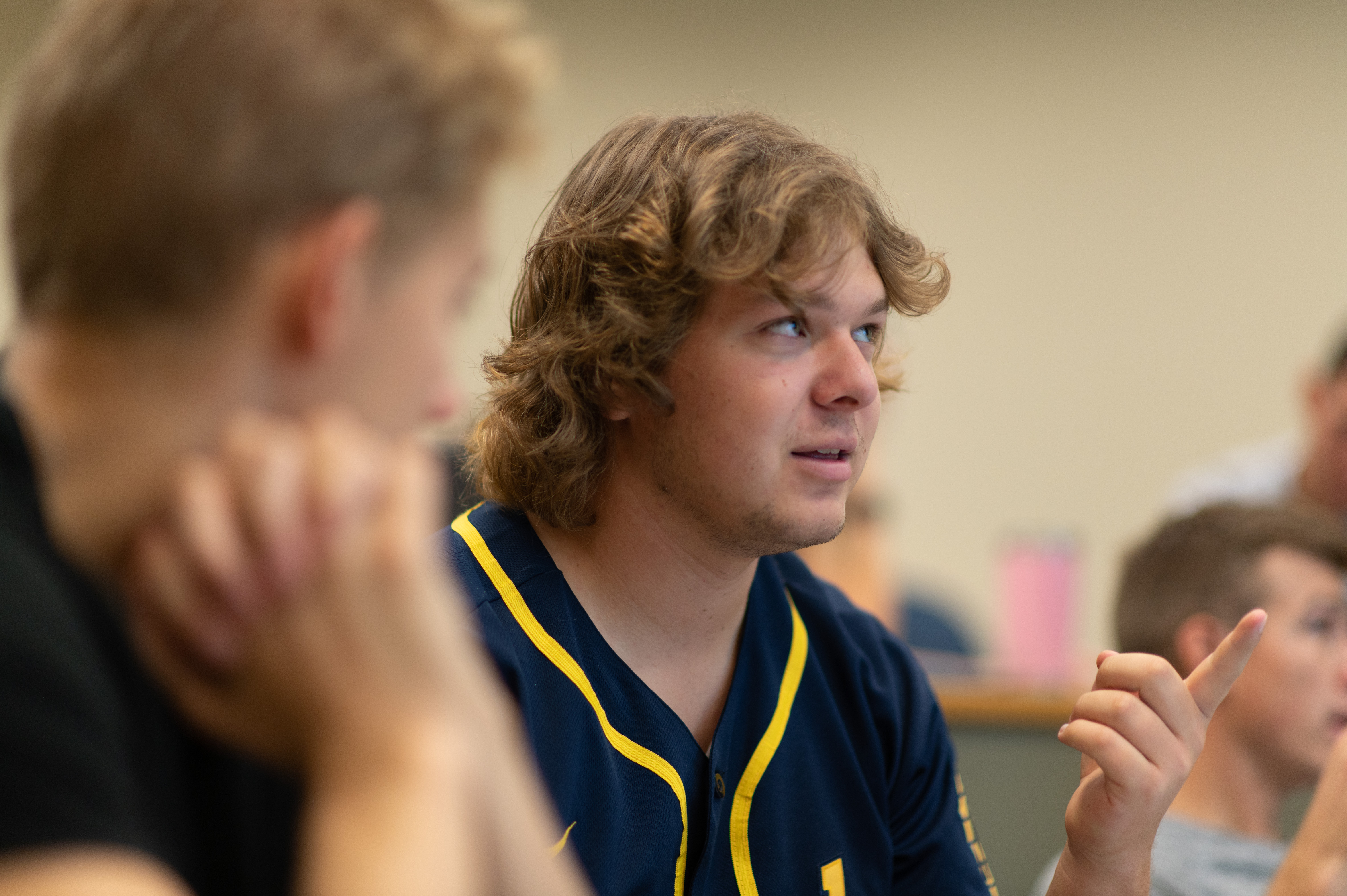 Male student points to the front of the classroom