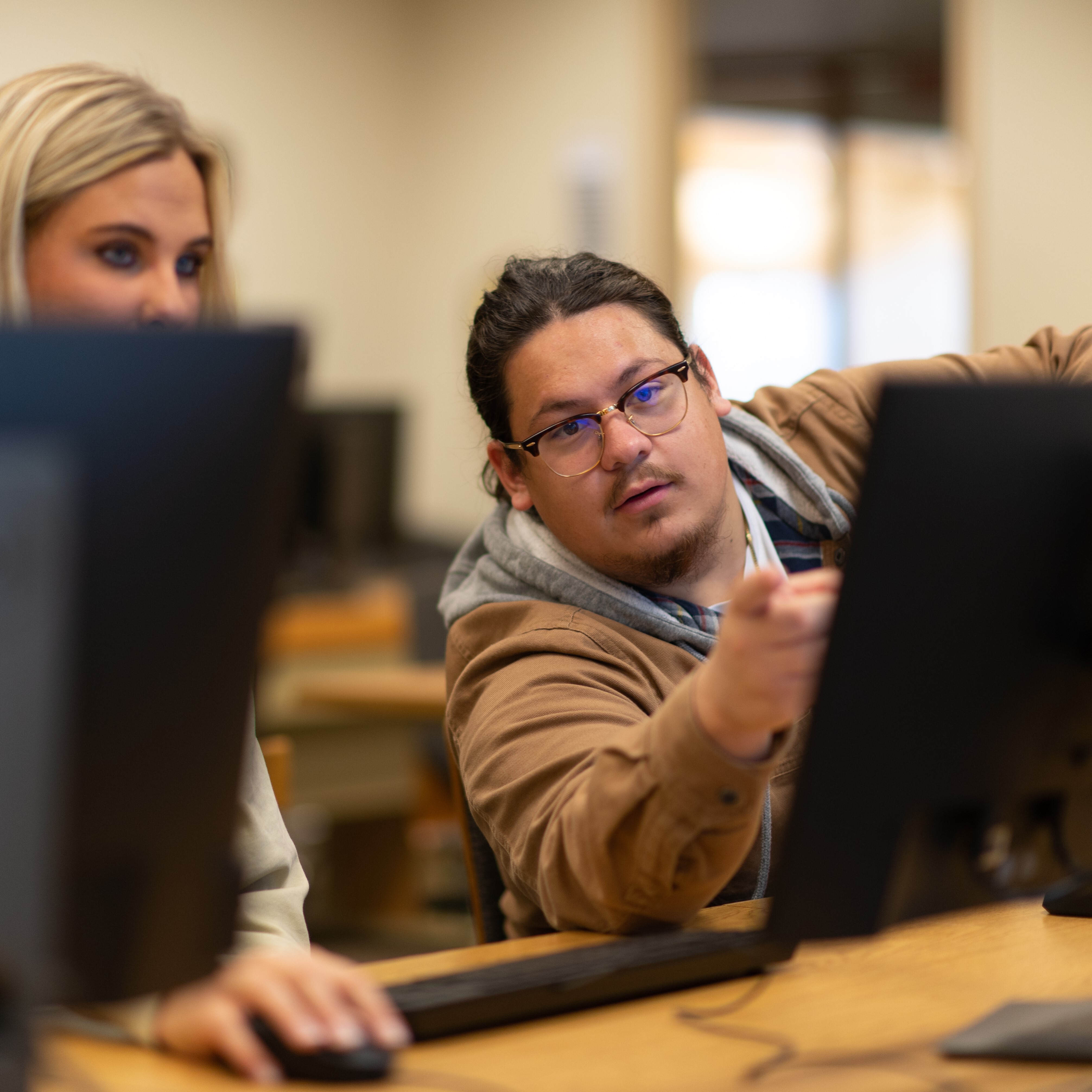 Male student assist the female on her computer