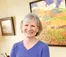 Judy Thompson smiles while holding paintbrushes