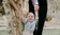 Parents help smiling toddler stand.