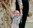 Parents help smiling toddler stand.