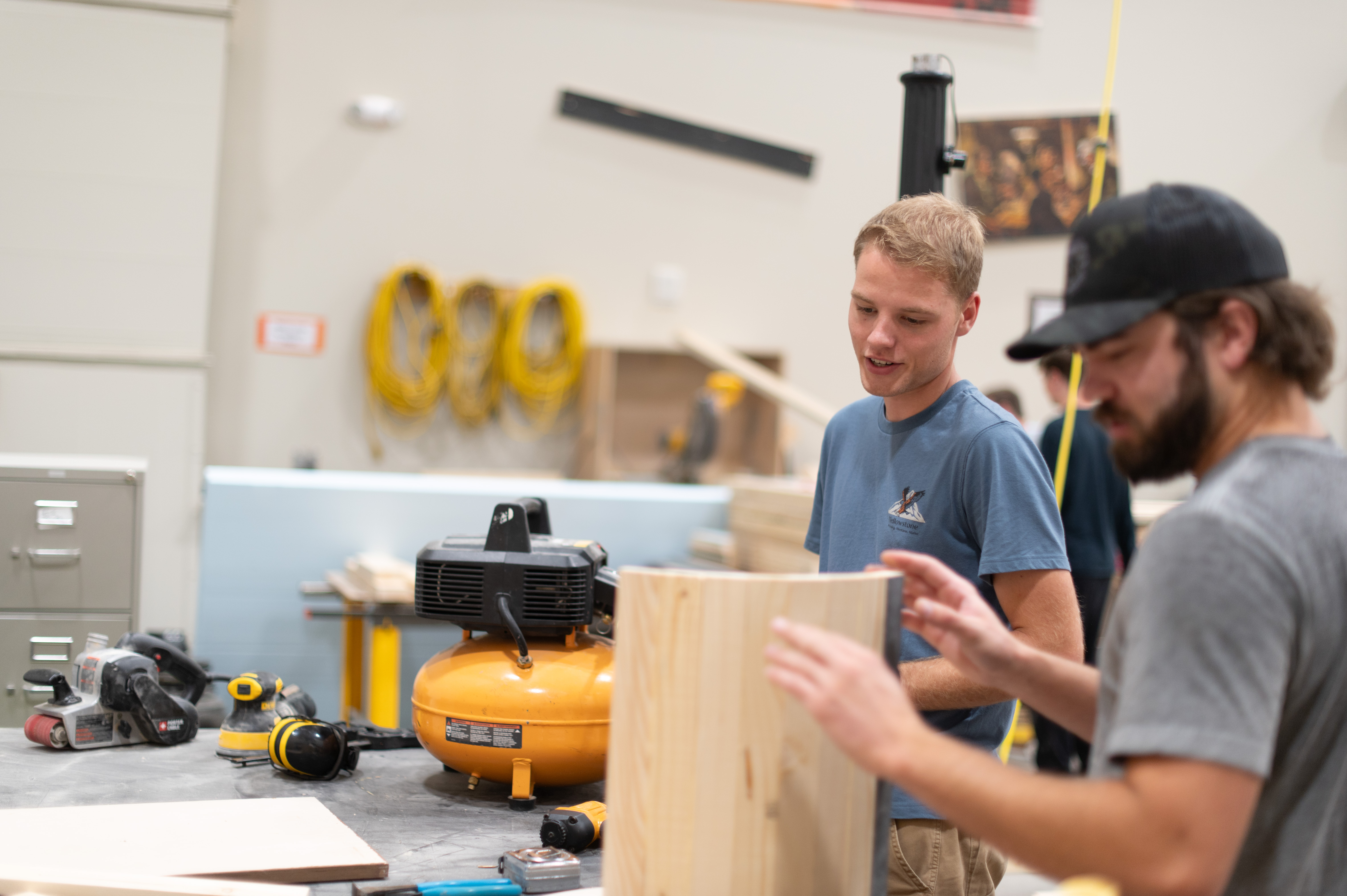 Male students work on a piece of wood