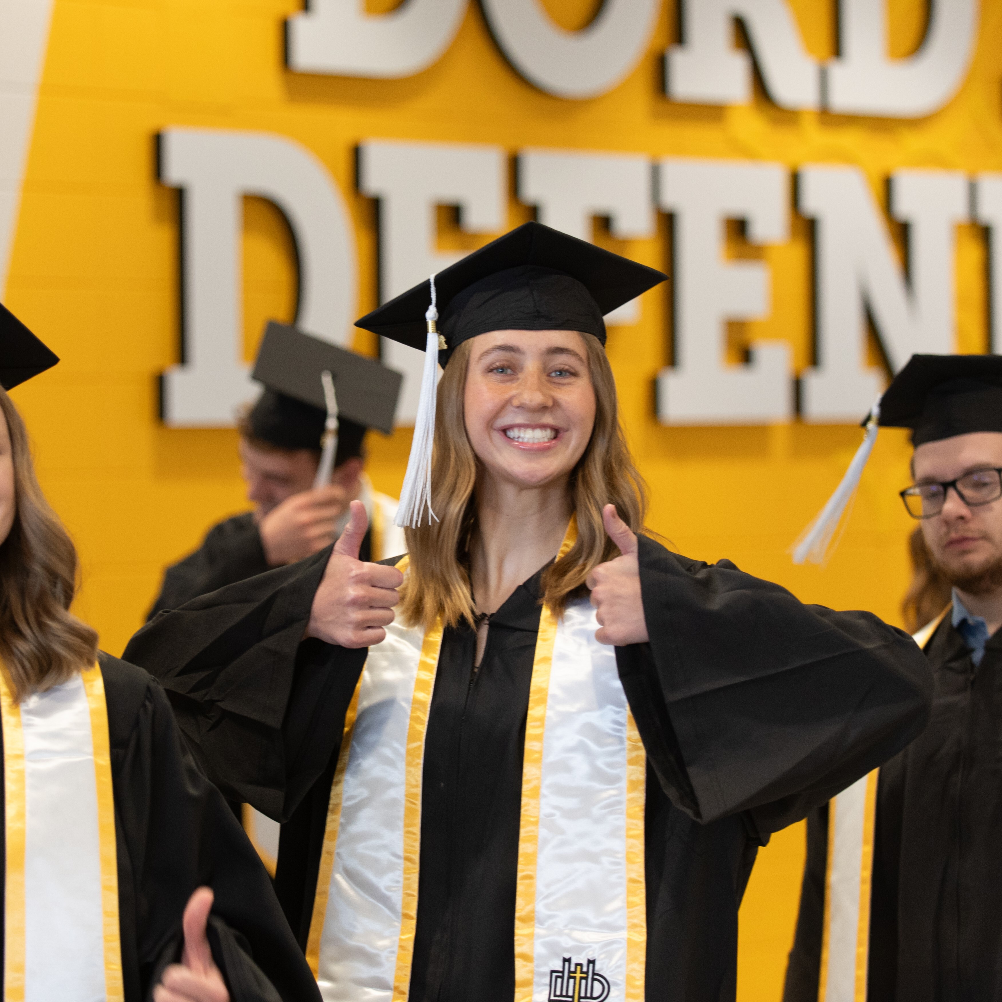 female student giving thumbs up when graduating