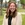 Young woman smiles enthusiastically outside building
