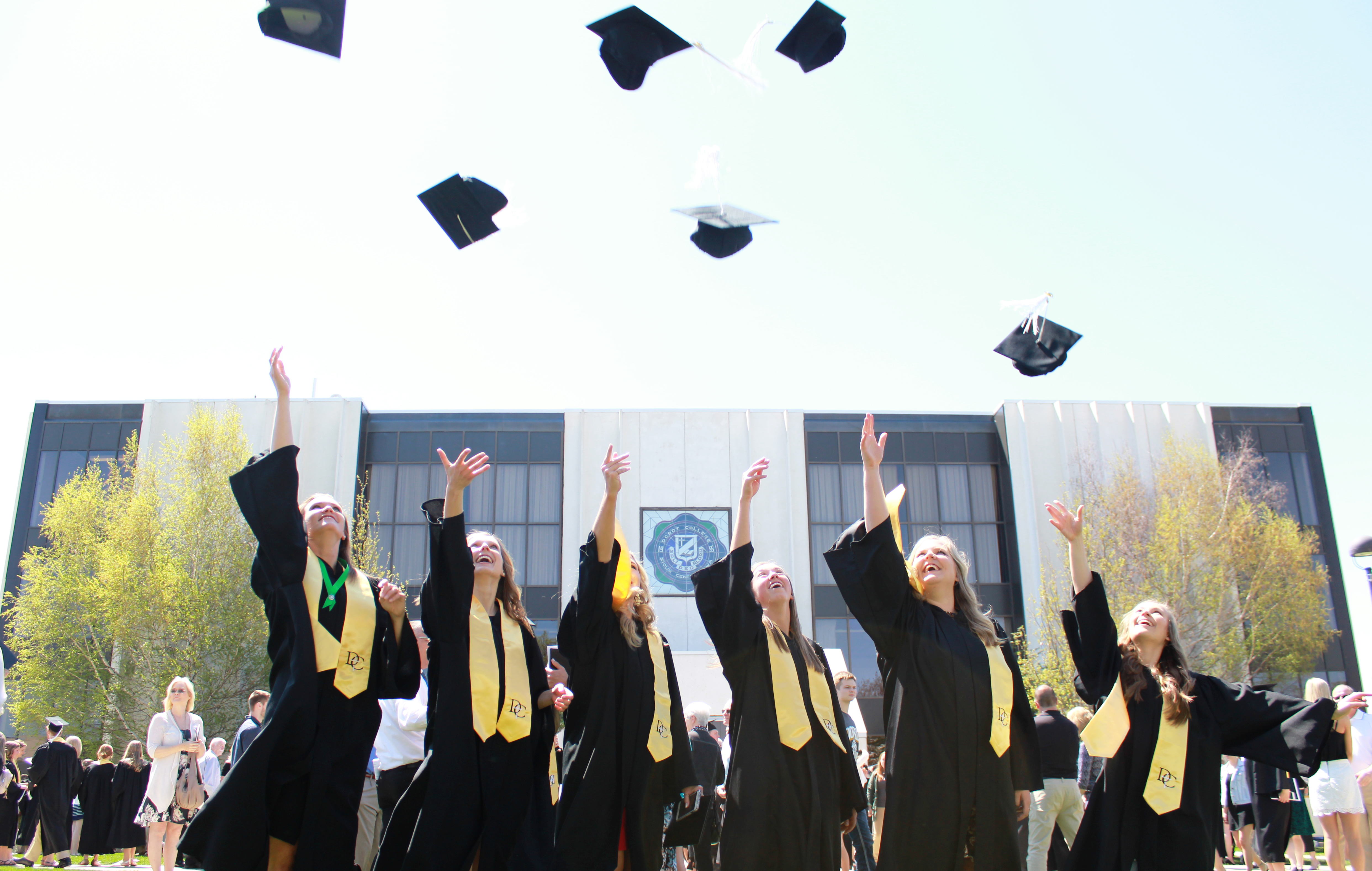 A picture of graduates in robes throwing their graduation caps in the air