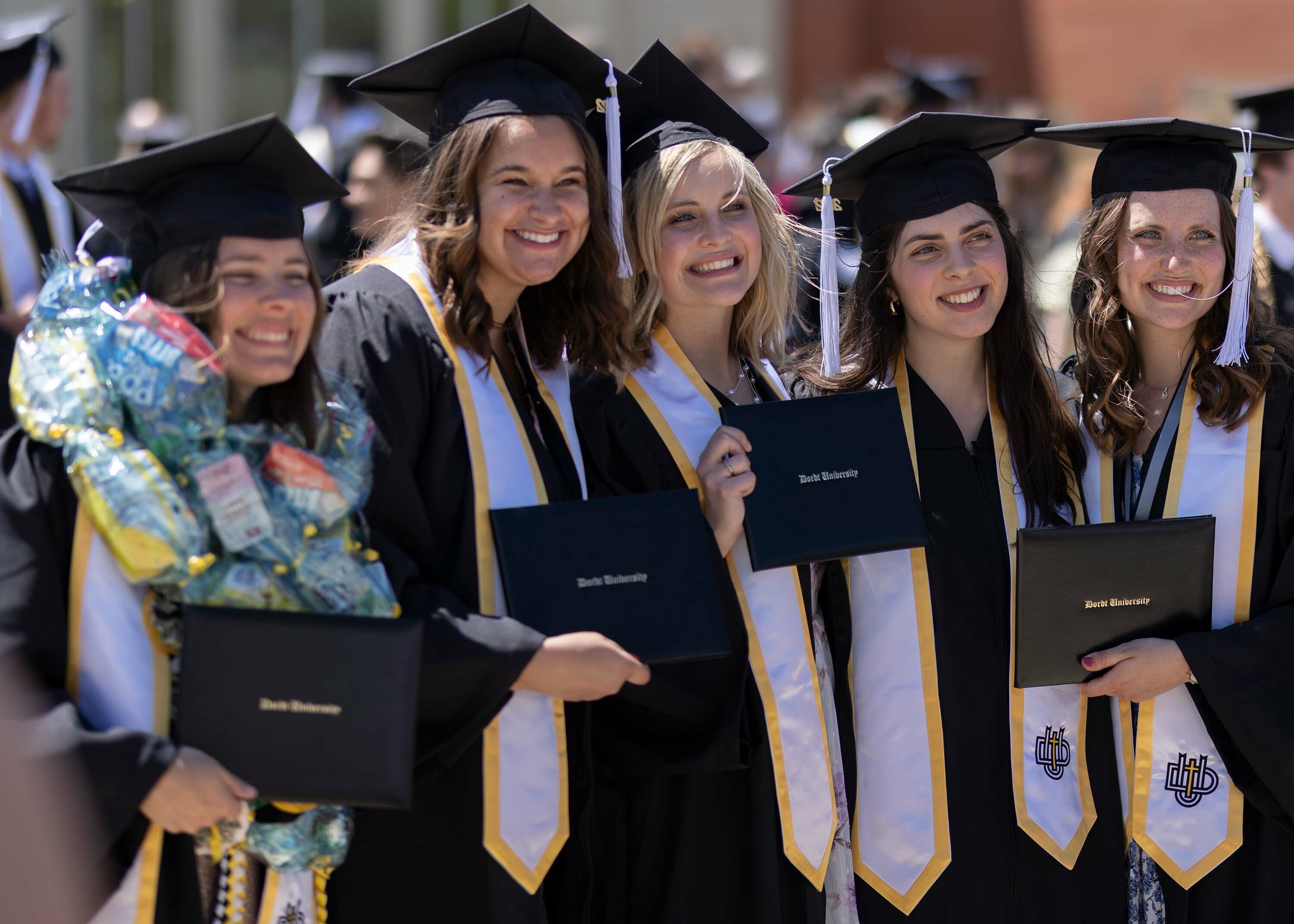 a group of female graduates smile for the camera after commencement